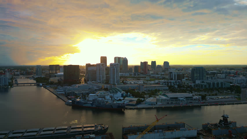 Twilight descends over downtown Tampa from an aerial view orbiting around capturing the sun