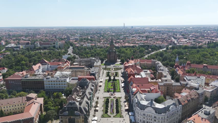 Scenic drone flyover of Victory Square leading to Timisoara’s Metropolitan Cathedral, highlighting urban architecture and landmarks.