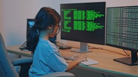 Young person working on programming code and data analysis in a modern workspace environment, focused on multiple computer screens displaying green text information - Powered by Shutterstock - Get 15% off with code: PIKWIZARD15