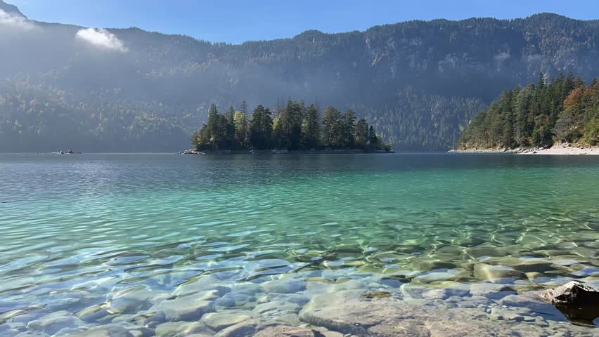 Timelapse of the small island Sasseninsel at picturesque lake Eibsee near Garmisch-Partenkirchen in the Bavaria region of Germany on a sunny autumn day