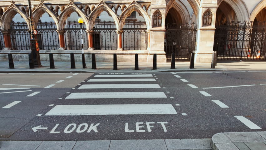 Pedestrian crossing leading to The Royal Courts of Justice, London, England, UK, an ornate Gothic Revival building with grand portals and carved stone
