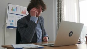 A young office specialist in a checkered blazer is focused on work, typing on a laptop and making a phone call at the same time. Business charts are visible on the whiteboard in the background. - Powered by Shutterstock - Get 15% off with code: PIKWIZARD15