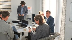 Young businessman stands with bundles of dollar bills near suitcase full of cash while colleagues at office table carefully count money, finance, profit and bonuses. - Powered by Shutterstock - Get 15% off with code: PIKWIZARD15