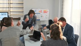 Excited manager opens suitcase full of dollar bills, throws money in the air, and distributes bundles to colleagues at office table, celebrating profit and success. - Powered by Shutterstock - Get 15% off with code: PIKWIZARD15