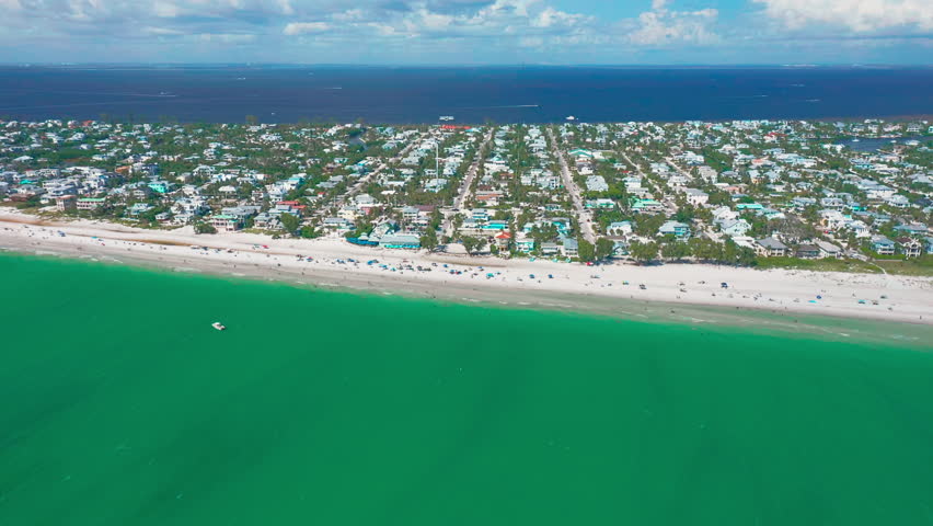 From the sky, Anna Maria Island glows with rows of pastel beach homes facing the emerald Gulf, where gentle waves and sunlit sand create a vivid portrait of coastal Florida beauty.