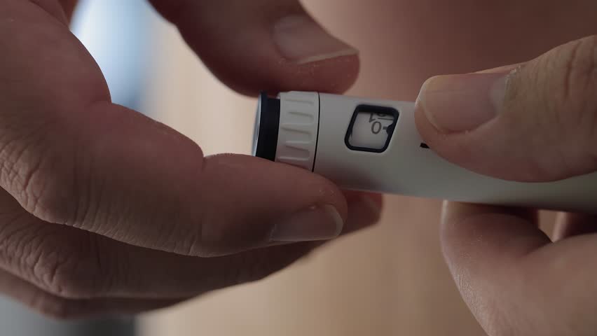 Medication closeup: Turning dosage knob on injection pen for dose