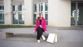 A stylish young woman in a vibrant pink blazer sits elegantly on a bench outside a modern building, showcasing her fashion sense with a chic outfit and accessories, exuding confidence - Powered by Shutterstock - Get 15% off with code: PIKWIZARD15