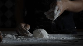 slow motion close up professional artisan baker chef sprinkle flour on raw loaf of dough while making homemade bread, pasta or pizza on wooden table in traditional bakery kitchen. restaurant cuisine - Powered by Shutterstock - Get 15% off with code: PIKWIZARD15