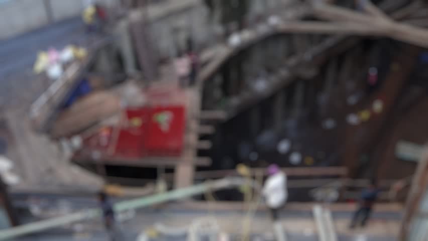 Bokeh view of people working on a contruction site of a skyscraper, Mumbai, India. Blurred background footage.