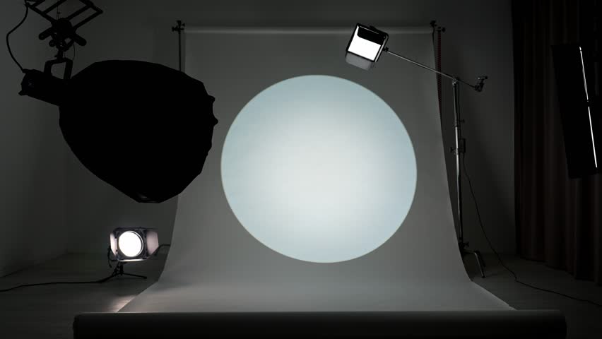Interior of a professional studio. Professional studio for photo and video production filming with modern lighting equipment, large white cyclorama background, testing colorful spotlight filters.