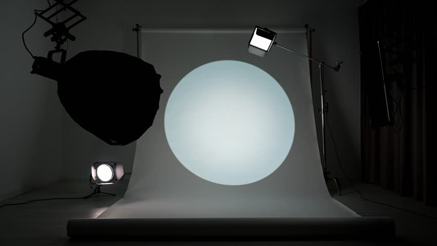 Interior of a professional studio. Professional studio for photo and video production filming with modern lighting equipment, large white cyclorama background, testing colorful spotlight filters.