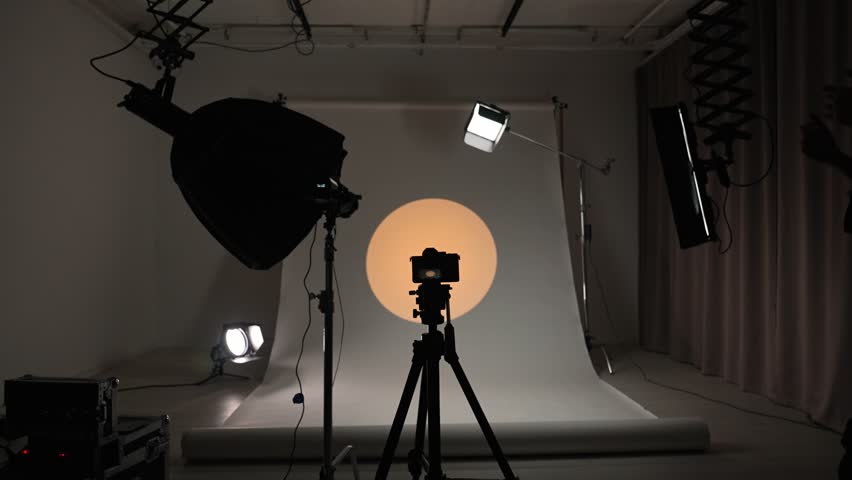 Interior of a professional studio. Professional studio for photo video filming with modern lighting equipment, large cyclorama, photographer and assistant finish work, taking off lights and cameras.
