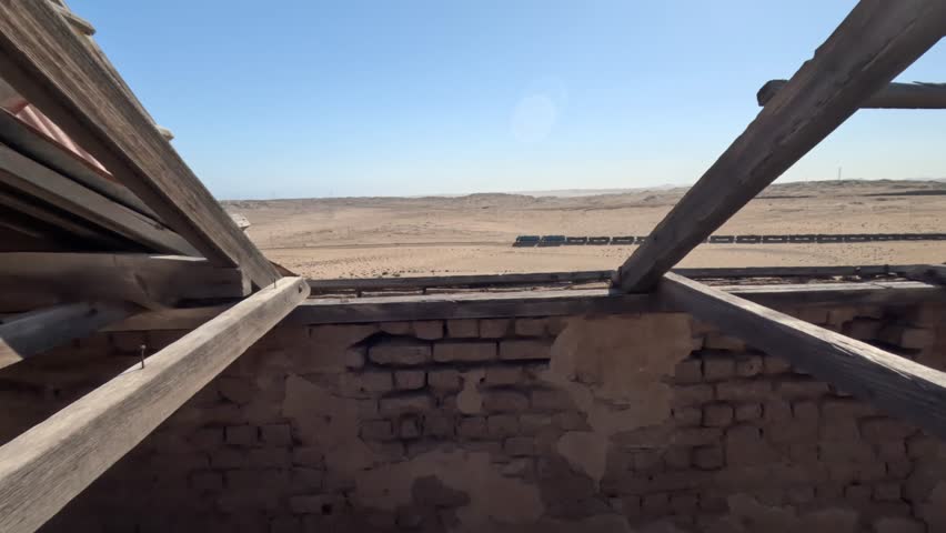 A train moves through the desert in Namibia, as seen from inside a ruined house. Freight train in the desert in Namibia