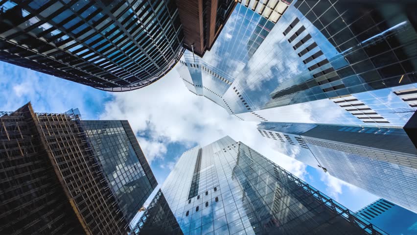 Rotating motion time lapse view of looking directly up at the skyline of the financial district in London with clouds passing by, background for modern architecture