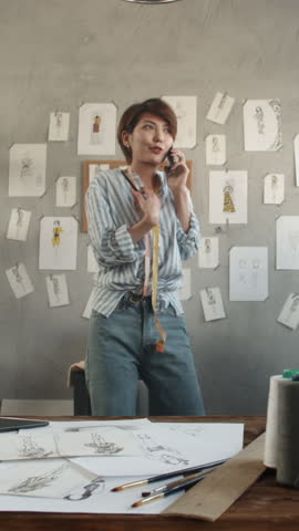 smiling female fashion designer talking on phone holding pencil expressing confidence joy and creative passion concept of sustainable lifestyle vertical slow motion fullhd video