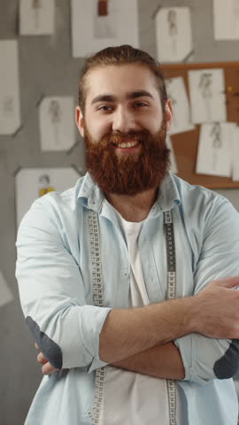 male fashion designer in atelier with measuring tape around neck looking at camera confident creative professional expressing purpose independence success vertical slow motion fullhd video