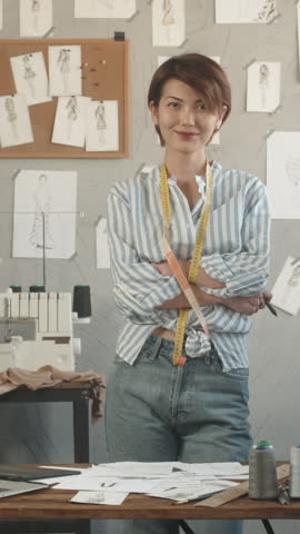 female fashion designer working on sketches then smiling to camera symbol of fulfillment creative independence and sustainable purpose vertical slow motion fullhd video