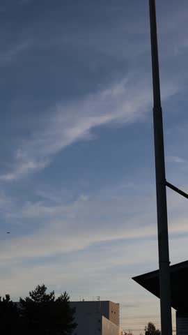 Vertical screen a jet aircraft flies high in the sky near a radar tower above trees and buildings creating a sense of motion airspace monitoring and modern technology under calm daylight
