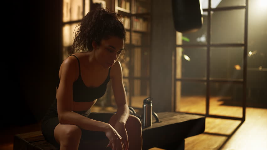 Tired African American female boxer wiping sweat after exhausting gym workout