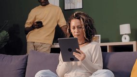 Young multiracial couple relaxing on the couch while using their tablet and smartphone - Powered by Shutterstock - Get 15% off with code: PIKWIZARD15