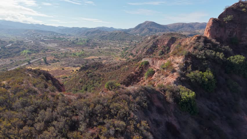 Drone view of sunlit canyon ridges, rocky outcrops, and sprawling valleys in the rugged terrain of Black Star Canyon Wilderness Park