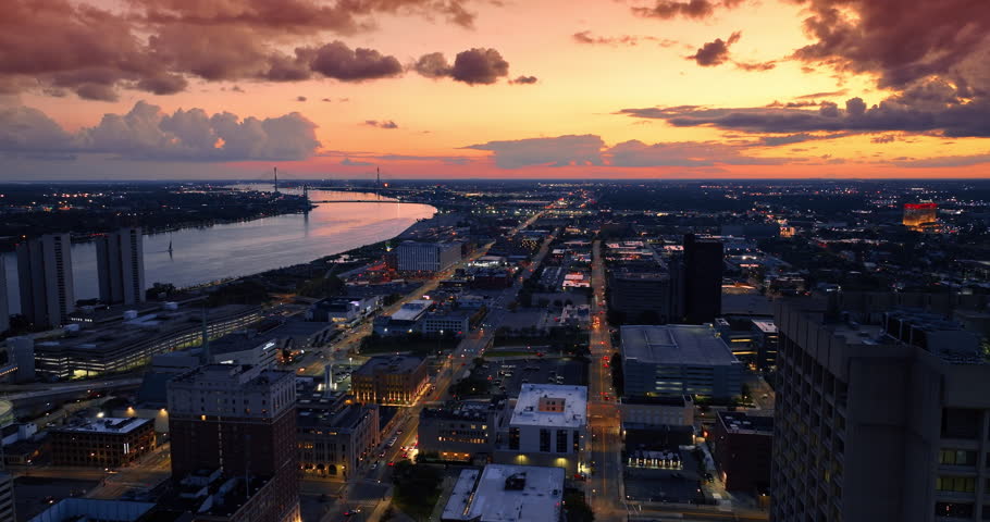 Moving over the city scenery along the Detroit River at dusk time. Amazing orange sky with cumulus clouds at backdrop.