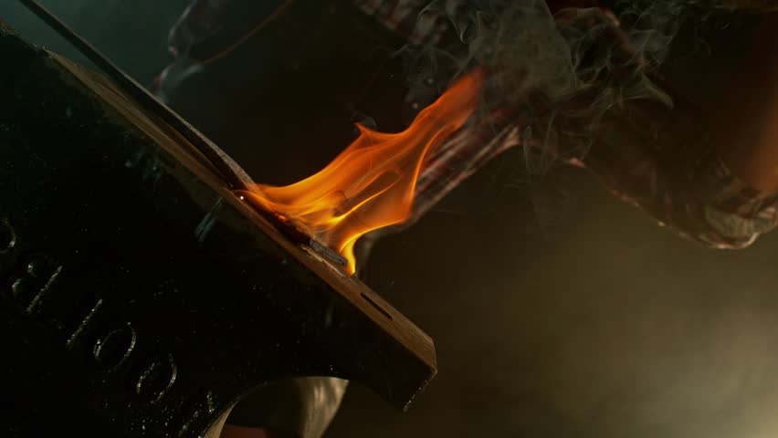 Close-up of blacksmith forging glowing hot iron on anvil with flying sparks. Super slow motion filmed on high-speed cinema camera at 1000 fps