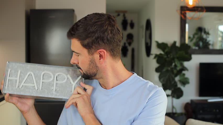 Cheerful man holding a "HAPPY" sign 