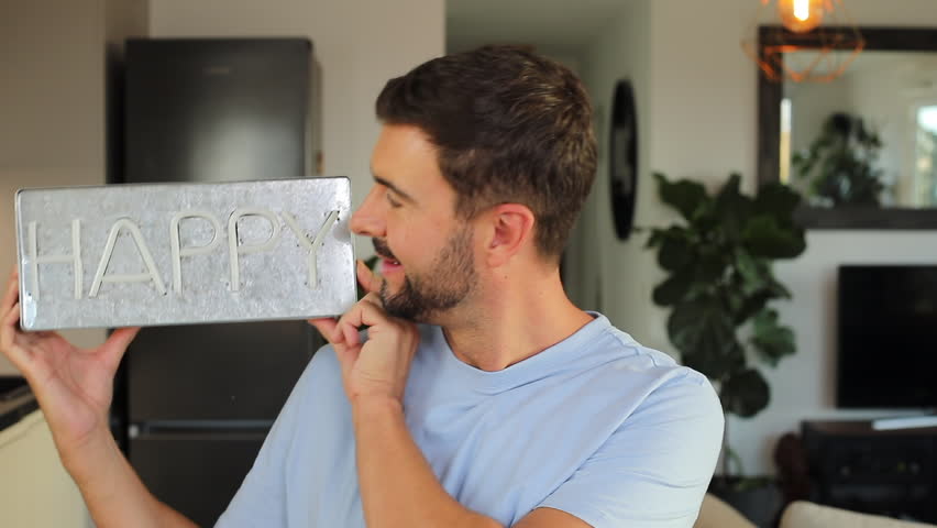 Cheerful man holding a "HAPPY" sign 