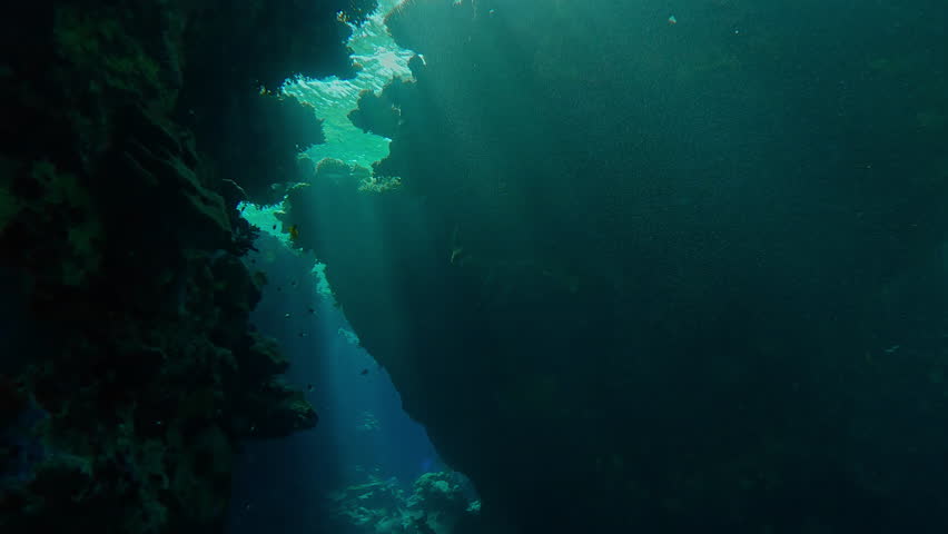 Bright sunbeams penetrate inside the cave, Slow motion, Illuminating the coral cave, light from above penetrates through cracks, Underwater cave inside coral reef