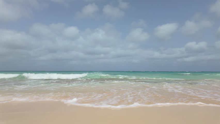 Atlantic Ocean waves breaking on a sandy beach and volcanic rocks on the Cape Verde island of Boa Vista.