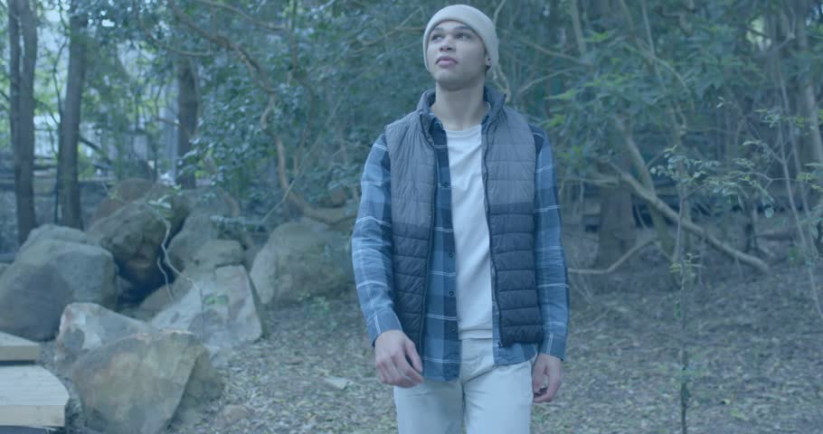 Man entering picnic area among benches as neon data streams glitching, scanning canopy in tech demo. Nature, solitude, digital, futuristic, serenity, exploration, technology