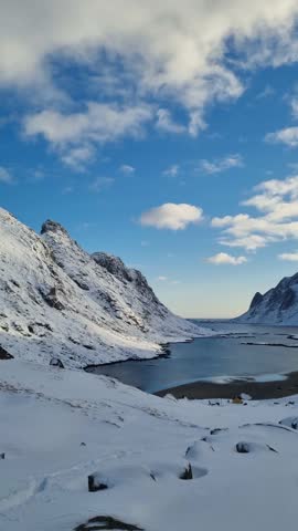 Abandoned village Vindstad in Norway on the Lofoten islands with red wooden houses in the foreground and mountains and the ocean in the background.