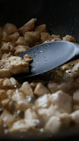 Golden brown chicken pieces sizzling in a pan	