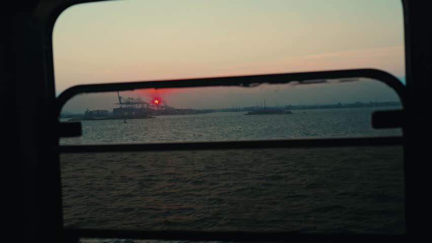 Industrial Port Cranes Silhouetted Against Sunset Sky Through Ferry Window