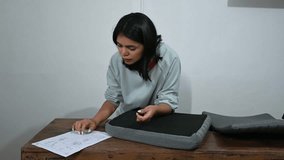 Latina woman assembling furniture at home following instructions, video 4k real time - Powered by Shutterstock - Get 15% off with code: PIKWIZARD15