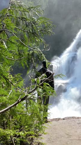 Majestic Waterfall in British Columbia, Canada, with a Hiker Admiring the Powerful Flow