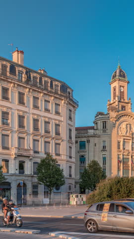 Hyperlapse of Place Antonin Jutard and the Mutuality Palace facade from the waterfront near Guillotiere Bridge in Lyon, France. Traffic flows on Quai Victor Augagneur under a blue sky timelapse