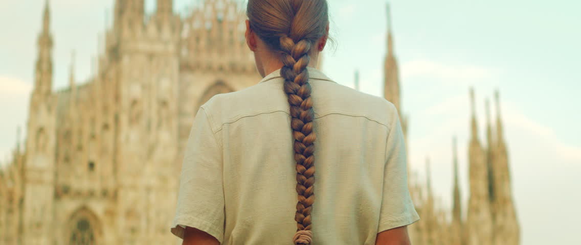 Back view of woman walking towards Duomo di Milano Cathedral, Italy