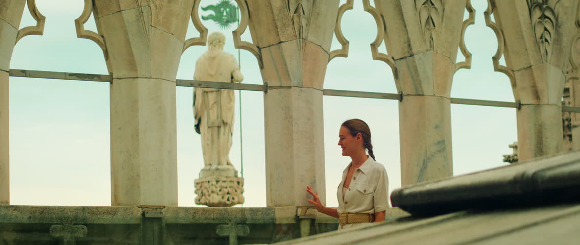 Woman on rooftop terrace of Duomo di Milano Cathedral near statue in Italy