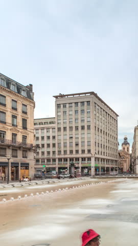Hyperlapse of Place de la Republique in the historical center of Lyon, France. The square is dominated by a large fountain, surrounded by historic buildings, with people sitting on benches timelapse