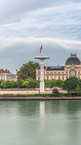Panoramic hyperlapse view of the Rhone River and its embankment, featuring the University Jean-Moulin in Lyon, France. Includes the University Bridge and waterfront under a partly cloudy sky timelapse