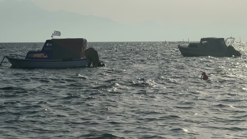 Fishing boats drift on the sea waves. Aegean Sea in Greece, Halkidiki