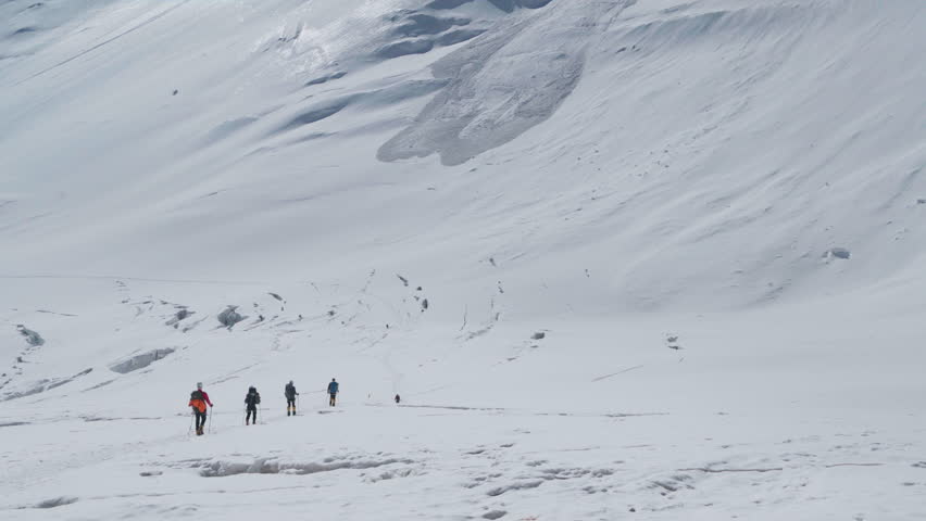Alpinists group snowy descending Lenin Glacier from Camp 2 5300m with vast panoramic view of "Frying Pan" in Pamir mountains Plateau. Active people concept. Lenin peak expedition route in Kyrgyzstan