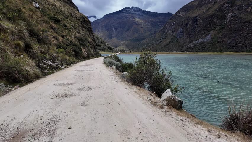 Yungay, Peru: Point of view footage of driving on small road between two Llanganuco lakes, mountain lake on Cordillera Blanca in Huascaran National Park in Peru with mountain in the background
