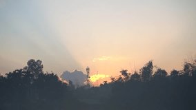 Scenic sunset view features a silhouette of trees with antenna tower and crepuscular rays. Time lapse of sun peaking through cloudscape. - Powered by Shutterstock - Get 15% off with code: PIKWIZARD15