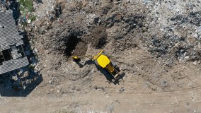 Overhead drone shot of a heavy equipment excavator working at a massive municipal solid waste (MSW) landfill, digging a cell for trash disposal. - Powered by Shutterstock - Get 15% off with code: PIKWIZARD15