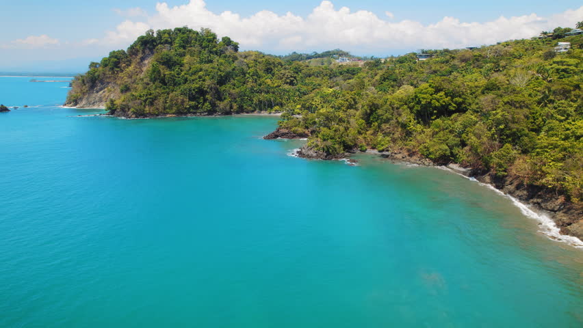 Crystal clear ocean waters embrace the verdant coastal landscape in Costa Rica