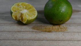 Close-up of Fresh Green Lime or Calamansi Fruit, One Whole and One Squeezed Half, on a Light Wooden Table with Water Droplets - Powered by Shutterstock - Get 15% off with code: PIKWIZARD15