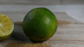 Close-up of Fresh Green Lime or Calamansi Fruit, One Whole and One Squeezed Half, on a Light Wooden Table with Water Droplets - Powered by Shutterstock - Get 15% off with code: PIKWIZARD15